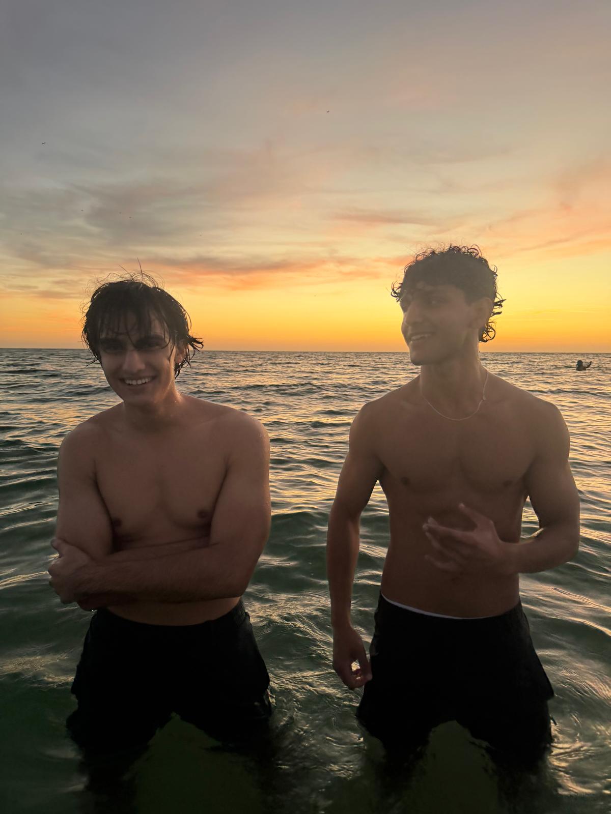 Aimal and Tunjay standing together at sunset by the ocean